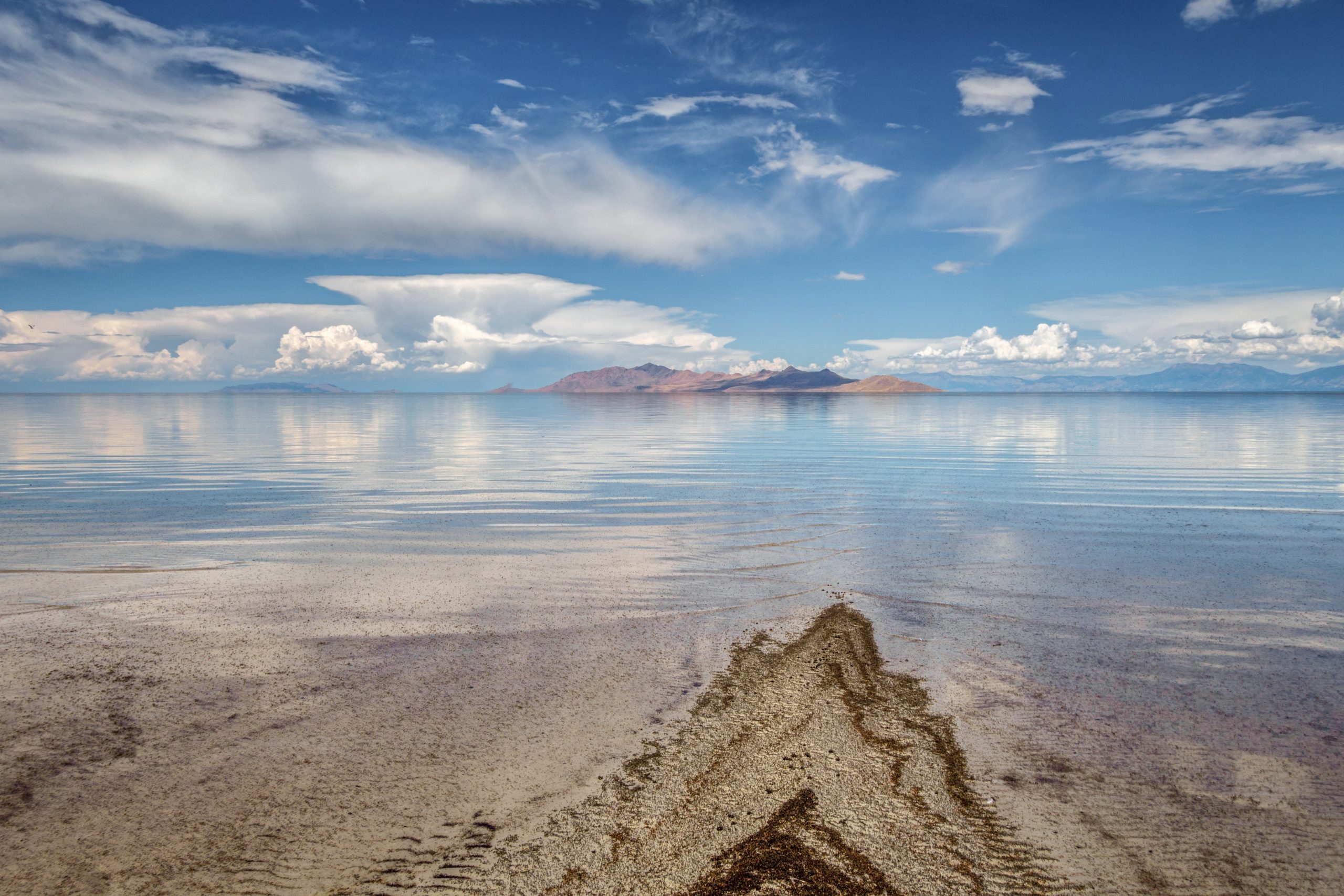 Calm lake reflecting clouds and distant mountains